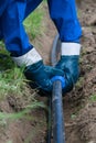 The working hands in gloves, put the plastic pipe in the dug trench in the ground