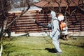 handyman wearing protective clothing using backpack mistblower for spraying organic pesticides