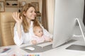 Working happy mother in maternity leave work remotely or study at home on computer while infant daughter hold papers and Royalty Free Stock Photo