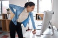 Working hard has its downsides. a young businesswoman experiencing back pain while working at her desk in a modern Royalty Free Stock Photo