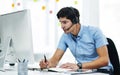 Working his hardest to find the best solution. a young businessman using a headset while working on a computer in an Royalty Free Stock Photo