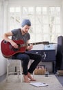 Working on his sense of timing and rhythm. a handsome young man playing a guitar at home.