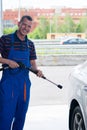 Working holds a gun in his hands to wash the car, and smiles