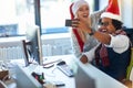 Working at holiday at office. Man and woman work at Christmas and  take selfie in santa hat Royalty Free Stock Photo