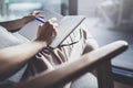 Working at home concept. Young business woman writing and taking notes while relax sitting in comfort chair at home Royalty Free Stock Photo