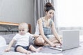 Working at home mom with baby are sitting on the bed. Internet and remote work Royalty Free Stock Photo