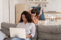 Work from home with naughty kid: young mom use laptop for business sit on sofa with bored son attack