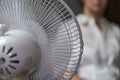 A working household fan on the table and a blurry image of the girl in the background