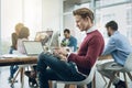 Working independently and as part of a team. a young businessman using a digital tablet at his desk in a modern office. Royalty Free Stock Photo