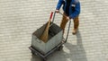 A working janitor comes with a trash cart and cleaning accessories: broom, dustpan.