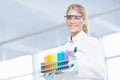 Working in the lab. Portrait of a beautiful female scientist carrying a tray of test tubes while smiling at the camera.