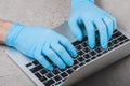 Working at a laptop in blue medical gloves. Protect your hands from bacteria and viruses when working on a laptop in public places Royalty Free Stock Photo