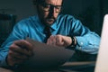 Working late night shift, businessman in dark office interior looking at his wristwatch Royalty Free Stock Photo