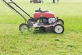 Working of lawn mover cutting grass leaves on garden field