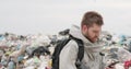 A working man against the backdrop of burning garbage. A lot of plastic bags thrown to the dump. From the plastic debris