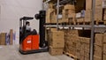 A working man moving cartons with fork lift truck in warehouse/store. Industrial. Transportation concept.