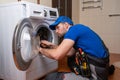 Working man plumber repairs a washing machine in home. Washing machine installation or repair. plumber connecting