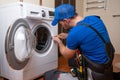 Working man plumber repairs a washing machine in home. Washing machine installation or repair. plumber connecting Royalty Free Stock Photo