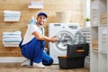 Working man plumber repairs washing machine in laundry Royalty Free Stock Photo