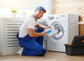 Working man plumber repairs washing machine in laundry Royalty Free Stock Photo