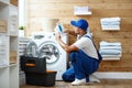 Working man plumber repairs washing machine in laundry Royalty Free Stock Photo