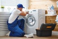 Working man plumber repairs washing machine in laundry Royalty Free Stock Photo