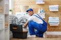 Working man plumber repairs washing machine in laundry Royalty Free Stock Photo