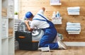 Working man plumber repairs washing machine in laundry Royalty Free Stock Photo