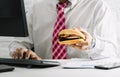 Working men do not have time urgent eating junk food hamburger while working in office
