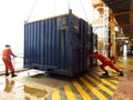 Working men taking off external load with lifting crane. Two constructors loading or discharging cargo. Workers remove cargo with
