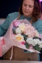 Working in modern floral shop, creative female business owner arranges stunning bouquet pink blooms