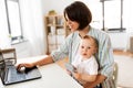 Working mother with baby boy and laptop at home Royalty Free Stock Photo
