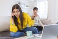 A working mother multitasking. Single mother with a kid trying to work. Worried woman working at home while her son is not letting