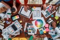 Working on a new project together. Top view of designers discussing sketches, choosing colors from palettes lying on the Royalty Free Stock Photo