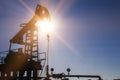 Working oil pump silhouette against sun and blue sky