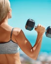 Working out in the fresh air. Rearview shot of an unrecognizable young woman exercising with dumbbells outside. Royalty Free Stock Photo