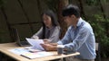 Working outdoor concept two male and female coworkers discussing relaxingly on the business topic with a laptop and documents on Royalty Free Stock Photo