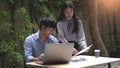 Working outdoor concept two male and female coworkers discussing relaxingly on the business topic with a laptop and documents on Royalty Free Stock Photo