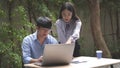 Working outdoor concept two male and female coworkers discussing relaxingly on the business topic with a laptop and documents on Royalty Free Stock Photo