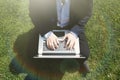 Working outside office.Young businessman in formalwear typing on laptop while sitting at city green grass outdoor Royalty Free Stock Photo