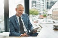 Working in a paperless office to match a modern business. a mature businessman working on a digital tablet in a modern Royalty Free Stock Photo