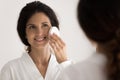 Millennial hispanic woman make tender face exfoliation by special sponge