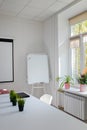 Working place, table, windowsill with potflowers, whiteboard, projector on wall. Minimalists clean office, work space. Vertical Royalty Free Stock Photo