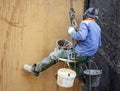 Working plasterer on the wall of the house working with climbing equipment