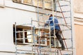 Working plasterer working on the scaffolding at the wall Royalty Free Stock Photo
