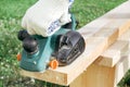 Working with a power tool. A builder is sawing a board at the construction site of a new house. Close-up on gloved hands holding a