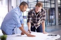 Working with precision to perfect their plans. two young architects working on blueprints in an office. Royalty Free Stock Photo