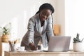 Busy black secretary taking notes while standing up near her desk