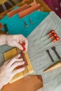 Working process of the leather bag for money or messenger in the leather workshop by master craftsman hands on the table Royalty Free Stock Photo