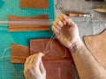 Working process of the leather bag for money or messenger in the leather workshop by master craftsman hands on the table Royalty Free Stock Photo